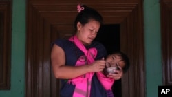 FILE - A woman feeds a child in the courtyard of her home, by the banks of Loktak lake in the northeastern Indian state of Manipur, India, June 18, 2021.