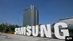 FILE - A worker waters the flower garden next to the logo of Samsung Electronics at the company's headquarters in Suwon on June 13, 2023. 