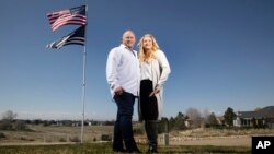 Jennifer and Tim Kohl poses for a photo in their front yard with the American flag and a thin blue line flag in Star, Idaho, on April 14, 2023. The couple recently moved to Idaho from the Los Angeles area. 