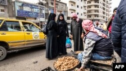 FILE - A truffle vendor speaks to customers at a market in Raqa, Syria, March 14, 2023.