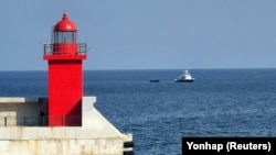 Sebuah kapal militer Korea Selatan menarik kapal Korea Utara yang membawa orang-orang yang diyakini berusaha membelot dari negara tersebut, ke pelabuhan di Yangyang, Korea Selatan, 24 Oktober 2023. (Foto: Yonhap via REUTERS)