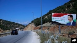 FILE - In this July 20, 2018, photo, a poster of Syrian President Bashar Assad with Arabic that reads "Welcome in victorious Syria" is seen on the border between Lebanon and Syria.