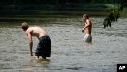 Cole Dunn, left, and Dylan Oliver try to escape the heat as they cool off in the Harpeth River, June 30, 2023, in Nashville, Tenn.