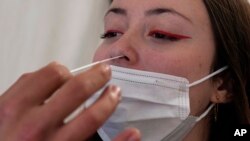 FILE - A woman gets a nasal swab at a COVID-19 testing site in Paris on Jan. 5, 2022. Researchers said on July 19, 2023, that people who have a specific genetic variant are twice as likely not to experience COVID-19 symptoms.