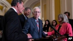Senate Minority Leader Mitch McConnell, R-Ky., center, is helped by Senator John Barrasso, R-Wyo., after freezing mid-sentence at the microphone during a news conference, at the Capitol in Washington, July 26, 2023.