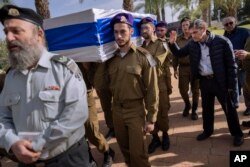 Yoram, right, father of Israeli soldier Lieutenant Yaacov Elian, bids farewell as soldiers carry his son's flag-draped casket during his funeral at Kiryat Shaul military cemetery in Tel Aviv, Israel, on Dec. 22, 2023.