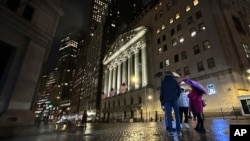People huddle outside the New York Stock Exchange on Nov. 21, 2023, in New York.