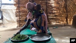 FILE - Iza Ali, 25, prepares a meal at the Jere camp for displaced people in Maiduguri, Nigeria, May 4, 2022. Nigeria declared a national emergency on food security July 13, 2023, as record inflation has made basic foods unaffordable for many.