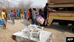 FILE - Suspected undocumented Zimbabweans climb into a South African National Defense Force vehicle following their arrest after attempting to smuggle food and furniture into Zimbabwe from South Africa, near Musina, Oct. 1, 2020. 