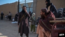 FILE - A Taliban security guard watches as food is distributed to Afghan people by the World Food Program at Nawabad Kako Sahib area in Baraki Barak district of Logar Province, Afghanistan, on Jan. 7, 2024.
