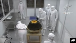 In this NASA image, technicians in a clean room examine the sample return capsule from the Osiris-Rex mission after it landed in the Utah desert on Sunday, Sept. 24, 2023. (NASA via AP)