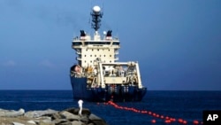 FILE - A ship rolls out fiber-optic cable, suspended from buoys, off La Guaira along the Venezuelan coast, Jan. 22, 2011. Undersea cables carry nearly all intercontinental internet traffic but are subject to many hazards, such as earthquakes and sabotage.