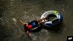 Someone uses an innertube to float on the Comal River, July 26, 2023, in New Braunfels, Texas, as the area continues to feel the effects of triple-digit tetemperatures.