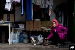 10 year old Khrystyna pets her cats in the yard of her house in Bohoyavlenka, Ukraine, on Sunday, April 9, 2023. Khrystyna's father died after last summer Russian shell hits his basement.