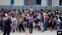 FILE - People gather across the street from a shopping center after a shooting May 6, 2023, in Allen, Texas.
