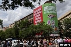 FILE - A far-right Vox party sign hangs from the exterior of a building, showing a hand dropping cards with symbols representing feminism, communism, the LGBTQ+ community, the squatters movement and the Catalan independence flag into a rubbish bin, in Madrid, Spain, May 20, 2023.