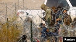 FILE - A migrant child seeking asylum kneels in front of a member of the Texas National Guard and asks to be allowed to enter the United States, as seen from Ciudad Juarez, Mexico, Jan. 30, 2024.