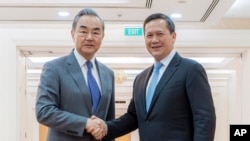 រូបឯកសារ៖ រដ្ឋមន្ត្រីការបរទេសចិនលោក Wang Yi និងនាយករដ្ឋមន្ត្រីកម្ពុជាលោក ហ៊ុន ម៉ាណែត ចាប់ដៃស្វាគមន៍គ្នា នៅវិមានសន្តិភាព រាជធានីភ្នំពេញ នាថ្ងៃទី២២ ខែមេសា ឆ្នាំ២០២៤។ (AKP via AP)