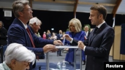 French President Emmanuel Macron casts his ballot flanked by French first lady Brigitte Macron at a polling station to vote in the second round of French parliamentary elections in Le Touquet-Paris-Plage, July 7, 2024. 