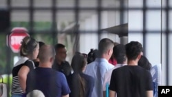 FILE - People wait to enter the Immigration and Customs Enforcement offices, July 26, 2023, in Miramar, Fla.