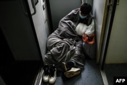 A couple rests on the floor as they ride a train from Beijing to Shijiazhuang on Feb. 6, 2024.