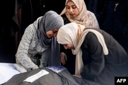 Palestinian women mourn over the wrapped body of a relative killed in overnight Israeli bombardment on the southern Gaza Strip at Al-Najjar hospital in Rafah on Feb. 8, 2024.