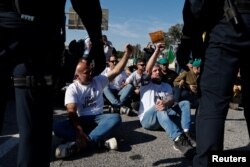 Spanish farmers gestures in front of police officers as they block access to the Castellon port during a protest against high costs, bureaucracy and competition from non-EU countries, in Castellon, Spain, Feb. 7, 2024.