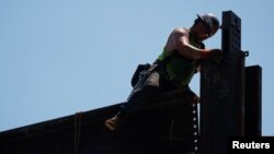 FILE - A worker installs steel beams on high-rise building under construction during a summer heat wave in Boston, June 30, 2021. 
