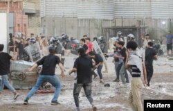 Para pengunjuk rasa bentrok dengan anggota polisi ketika mereka berkumpul di dekat kedutaan Swedia di Baghdad beberapa jam setelah kedutaan itu diserbu dan dibakar menjelang pembakaran Al-Qur'an yang diperkirakan terjadi di Stockholm, di Baghdad, Irak, 20 Juli 2023. (Foto: REUTERS/Ahmed Saad)