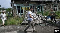 A member of a volunteer medics team walks past a destroyed building in the village of Staryi Karavan, Donetsk region, on July 21, 2023, amid the Russian invasion of Ukraine. 
