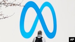 FILE - A person stands in front of a Meta sign outside the company's headquarters in Menlo Park, Calif., March 7, 2023. Facebook's decision to block news sharing on its platforms in Canada has cost small local news outlets a good chunk of their audiences.