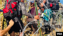 Migrantes en Eagles Pass, en Texas, Estados Unidos, se apoyan durante la travesía que hacen para intentar llegar a EEUU. [Foto: Salomé Ramírez, VOA]