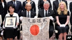USS Lexington Museum executive director Steve Banta, center right, and Toshihiro Mutsuda, center left, the elderly son of Japanese soldier Shigeyoshi Mutsuda, hold Mutsuda's good luck flag after the handover ceremony at Yasukuni shrine in Tokyo, Japan, on July 29, 2023.