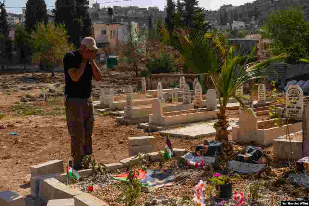 A man prays by the graves of four young men who were killed in an attack by Jewish settlers in the small town of Qusra, Oct. 24, 2023. 