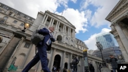 FILE - A man walks past the Bank of England at the financial district in London, May 11, 2023.