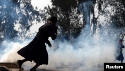 Farmers, who are marching towards New Delhi to press for better crop prices promised to them in 2021, run for cover amidst tear smoke fired by police to disperse them at Shambhu, a border crossing between Punjab and Haryana states, India, Feb. 13, 2024.