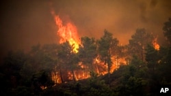 FILE - Flames rise during a forest fire on the island of Rhodes, Greece, July 22, 2023. 