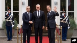 NATO Secretary General Jens Stoltenberg, left, and Dutch Prime Minister Mark Rutte, right, welcome Lithuania's President Gitanas Nauseda in The Hague, Netherlands, June 27, 2023. 
