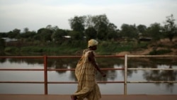 Une femme traverse le pont sur la rivière Mpoko le 13 avril 2024, RCA.