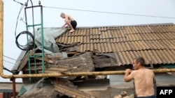 A man repairs a roof of a house damaged by a Russian missile after a night strike in Odesa on July 18, 2023. 
