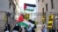 Demonstran pro-Palestina mengibarkan bendera Palestina di depan gerbang masuk Columbia University saat para aktivis pro-Palestina menggelar aksi perkemahan di dalam kampus tersebut di New York pada 22 April 2024. (Foto: AFP/Charly Triballeau)