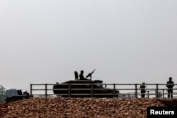 Military personnel stand guard as a stream of people queued at a border crossing to flee Myanmar, after the strategically-vital town of Myawaddy adjoining Thailand fell to anti-junta resistance, in Mae Sot, Tak province, Thailand, April 12, 2024.
