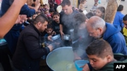 Palestinians collect food at a donation point provided by a charity group in the southern Gaza Strip city of Rafah, Dec. 6, 2023.