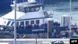Migrants are escorted ashore from a UK Border Force vessel in Dover, southeast England, June 15, 2023, after having been picked up at sea while attempting to cross the English Channel.