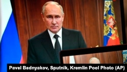 Presiden Rusia Vladimir Putin terlihat di monitor ketika dia berpidato di hadapan warga setelah Yevgeny Prigozhin, pemilik perusahaan militer Grup Wagner, menyerukan pemberontakan bersenjata, di Moskow, Rusia, Sabtu, 24 Juni 2023. (Foto: via AP)