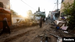 Palestinians walk amid damage after the Israeli army's withdrawal from the Jenin camp in Israeli-occupied West Bank, July 5, 2023. 