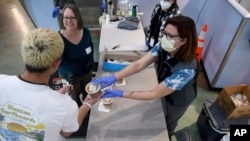 FILE - Joy McCalister, left, and Stevi Soles serve soup to a migrant at a makeshift shelter in Denver, Jan. 6, 2023. Five U.S. mayors want a meeting with President Joe Biden to ask for help controlling the continued arrival of large groups of migrants to their cities. 