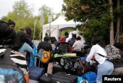 FILE - A line of asylum-seekers who identified themselves as from Haiti, wait to enter into Canada from Roxham Road in Champlain, New York, Aug. 7, 2017.
