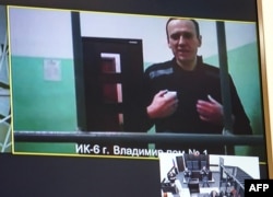 FILE - A screen shows jailed Kremlin critic Alexey Navalny as he arrives at a court in Moscow, on Sept. 26, 2023.