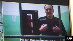 FILE - A screen shows jailed Kremlin critic Alexei Navalny as he arrives to listen to a hearing on an appeal lodged against a court decision to jail him for 19 years in a maximum security prison on extremism-linked charges, at a court in Moscow, Russia, Sept. 26, 2023.